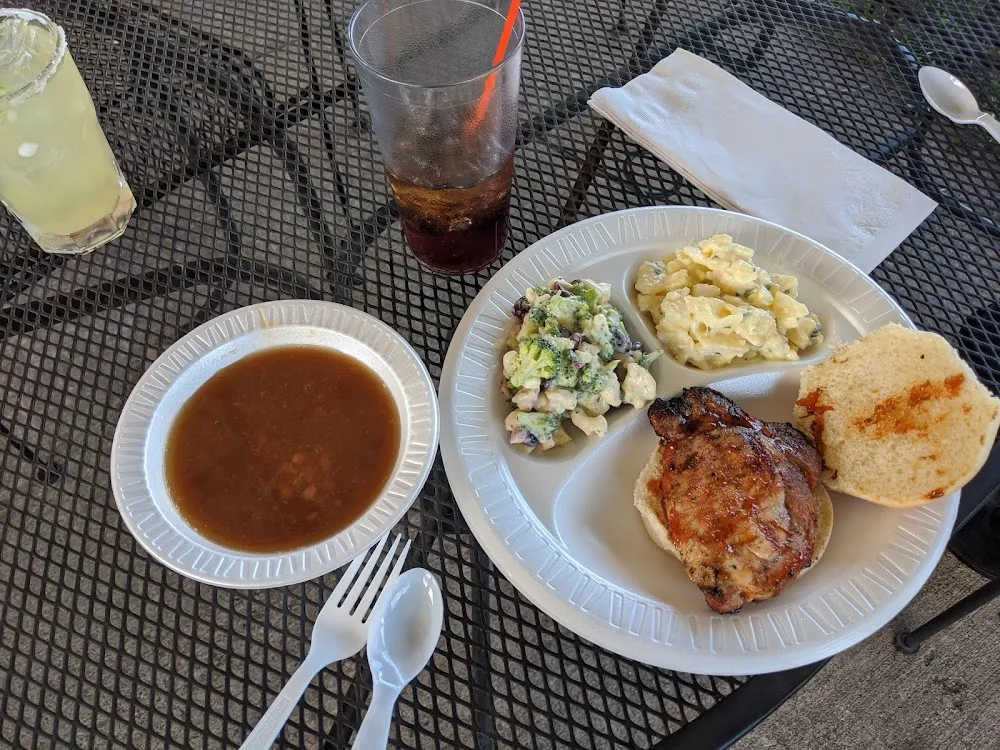Grilled Pork Chop on Bun Potato Salad Broccoli Cauliflower Salad and Beans in the Bowl